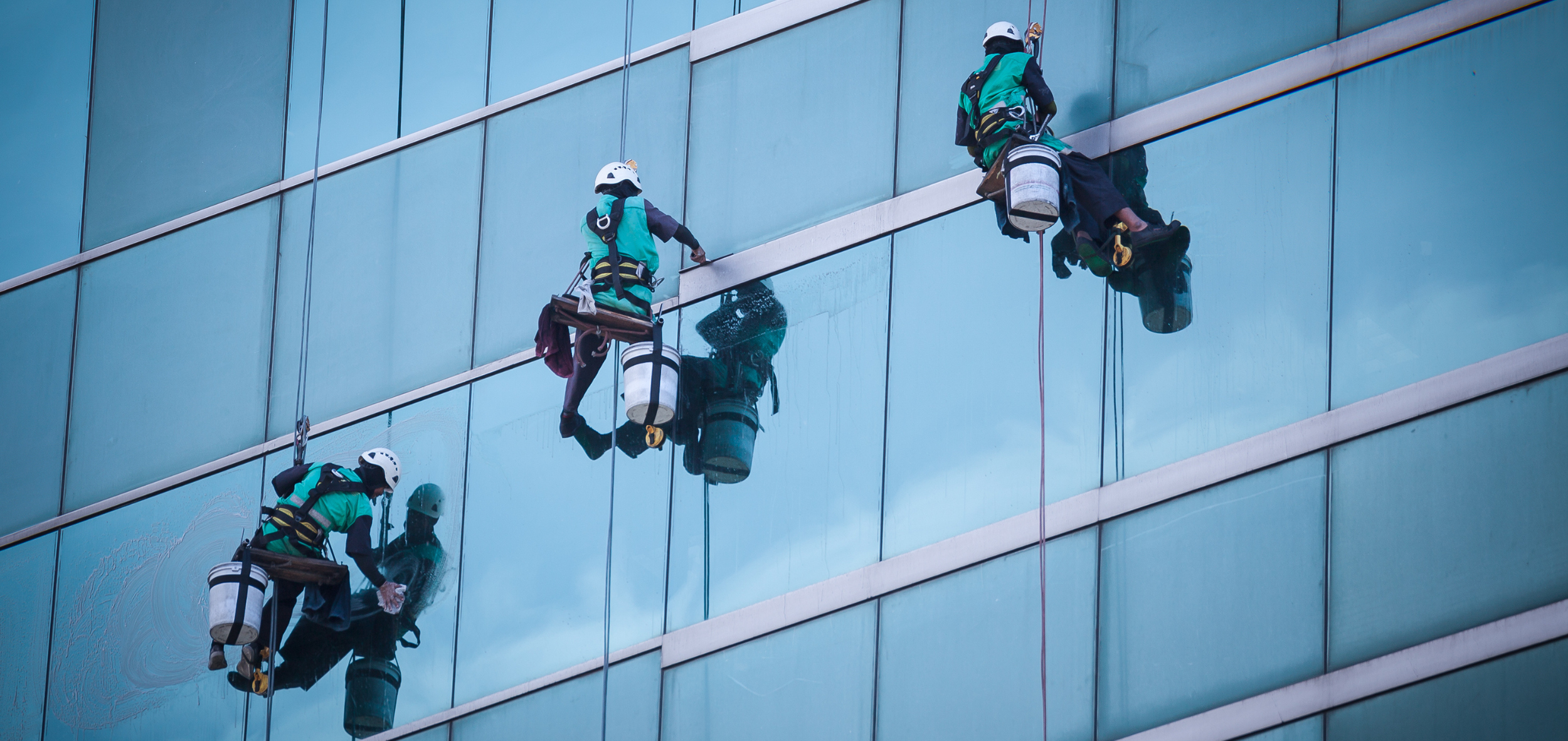 Group of workers cleaning windows service on high rise building